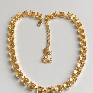 May include: A gold necklace with a chain and a row of round settings for rhinestones.