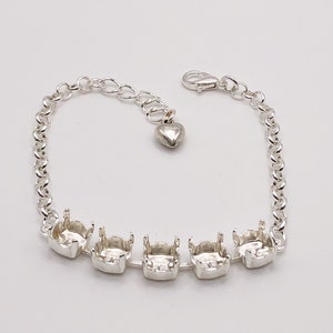 May include: Silver bracelet with a heart charm and five empty settings for rhinestones. The bracelet is made of a delicate chain.