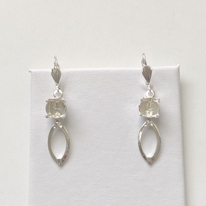 May include: A pair of silver earring blanks with a teardrop-shaped dangle and a round bezel setting.