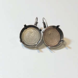 May include: A pair of silver earring settings with a round bezel. The settings are open on the back and have a loop for attaching to an earring hook.
