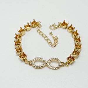 May include: Gold-toned bracelet featuring an infinity symbol embellished with clear crystals. The bracelet has a series of settings for gemstones and a clasp closure. The bracelet is designed for jewelry making.