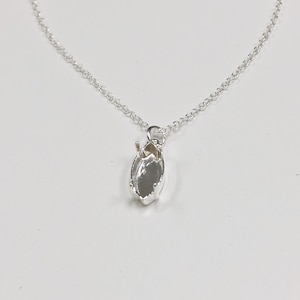 May include: A silver chain necklace with a pendant that is a silver setting for a marquise-shaped gemstone.