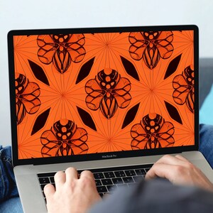 Könnte beinhalten: Eine Person, die einen Laptop mit einer leuchtend orangefarbenen und schwarzen geometrischen Mustertapete verwendet. Der Laptop ist geöffnet und die Person tippt auf die Tastatur.