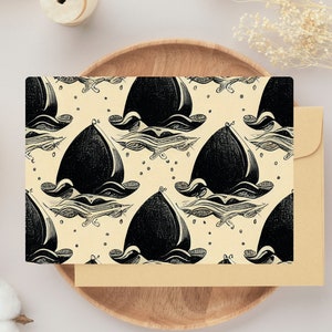 Puede incluir: Una tarjeta beige con un patrón repetitivo en blanco y negro de peces estilizados. Los peces están dibujados en un estilo geométrico y parecen nadar en un círculo.