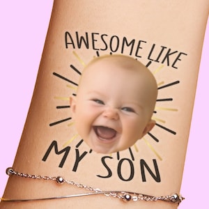 May include: A temporary tattoo with a sunburst design and the text "Awesome Like My Son". A baby's face is in the center of the sunburst.