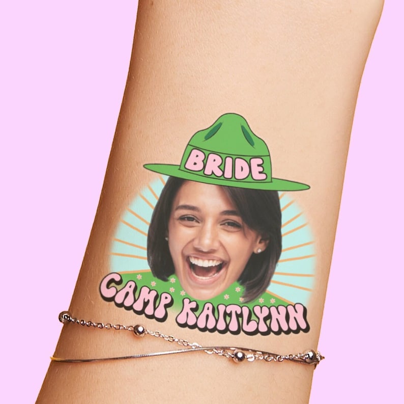 Puede incluir: Un tatuaje temporal que representa a una mujer con un sombrero verde de guardabosques con la palabra "BRIDE" en &eacute;l. El tatuaje tambi&eacute;n incluye el texto "CAMP KAITLYNN" en una fuente retro.