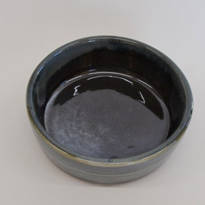 K&ouml;nnte beinhalten: Eine dunkelblaue Keramiksch&uuml;ssel mit hellblauem und gr&uuml;nem Glase. Die Sch&uuml;ssel hat einen glatten, abgerundeten Innenraum und einen leicht ausgestellten Rand.
