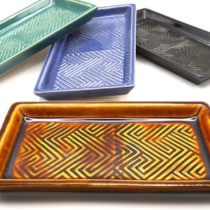May include: Four ceramic rectangular trays with a maze pattern. The trays are in shades of green, blue, gray, and brown.