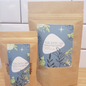 May include: Two brown paper bags with a zipper closure. The bags contain loose leaf tea. The larger bag has a label that says "NIGHTCAP Premium Loose Leaf Tea SLEEP 0.5 oz (3-6 servings)". The smaller bag has a label that says "NIGHTCAP Premium Loose Leaf Tea SLEEP 0.5 oz (3-6 servings)".