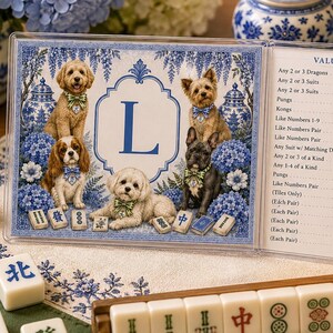 May include: A clear acrylic Mahjong score card featuring a blue letter L, illustrations of five dogs wearing patterned bow ties, and blue hydrangea flowers. The right side displays a printed list of game values and multipliers for various tiles.
