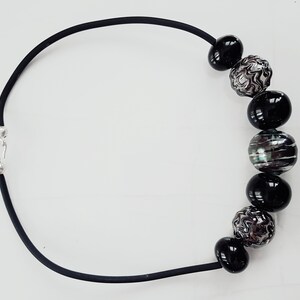 May include: A black necklace with a silver clasp and black and silver beads.