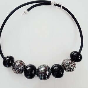 May include: A black choker necklace with silver and black beads. The beads are round and have a variety of patterns.