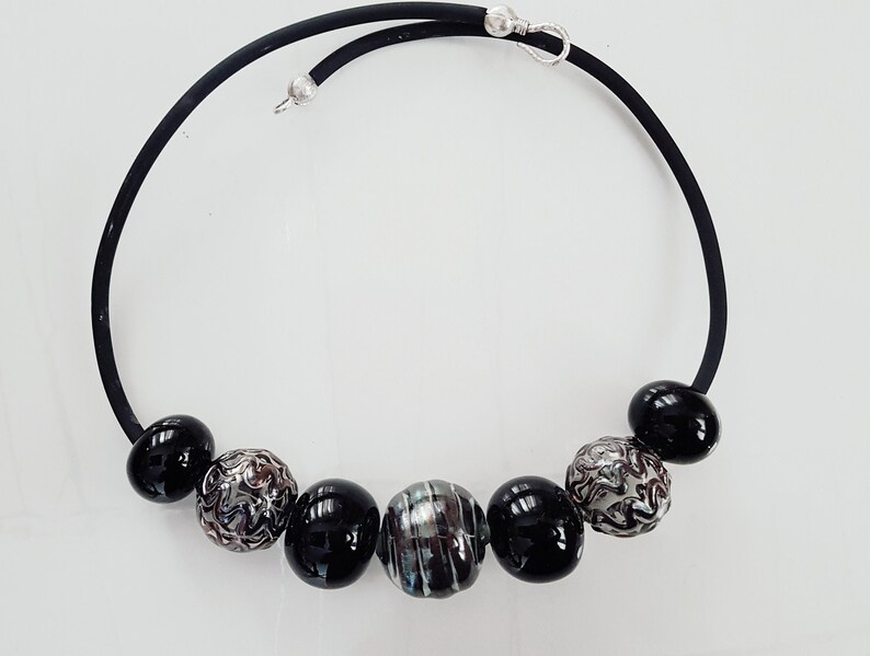 May include: A black choker necklace with silver and black beads. The beads are round and have a variety of patterns.