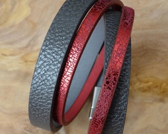 May include: A multi-layered bracelet with two black leather bands and one red leather band with a metallic finish.