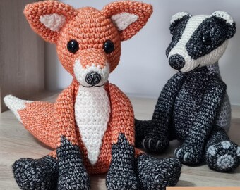 May include: A crochet fox and a crochet badger sitting side by side. The fox is orange, white, and black with black eyes. The badger is black, white, and gray with black eyes. The image includes the text BUNDLE and 5 x patterns.