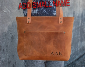 May include: A brown leather tote bag with a front pocket and a personalized monogram that says "AAK".