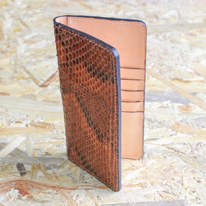 May include: A brown leather wallet with a snakeskin pattern and multiple card slots.