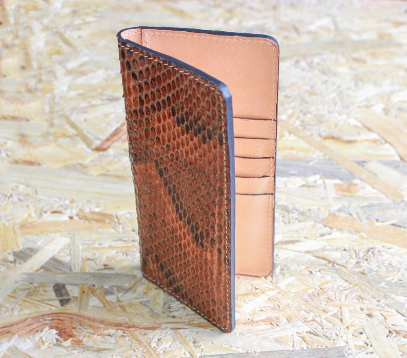 May include: A brown leather wallet with a snakeskin pattern and multiple card slots.