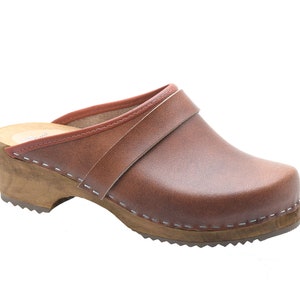 Pode incluir: Sapatilha de couro marrom com salto de madeira e uma costura ao redor da sola.