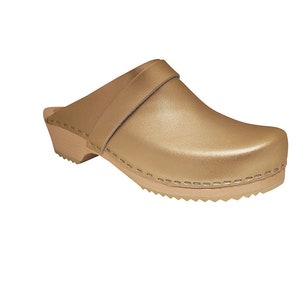 Pode incluir: Sapatilha de couro dourado com sola de madeira e uma tira na parte superior.