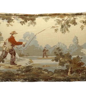 May include: A tapestry pillow featuring a scenic landscape with two figures fishing in a river. The pillow is beige with brown and green accents. The figures are wearing traditional clothing and are holding fishing rods.