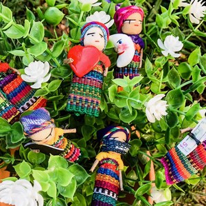 Puede incluir: Una colecci&oacute;n de mu&ntilde;ecas tejidas de colores con varios dise&ntilde;os y patrones. Las mu&ntilde;ecas est&aacute;n hechas de tela y tienen caras bordadas. Algunas de las mu&ntilde;ecas sostienen objetos, como un coraz&oacute;n, una luna y un trozo de papel.