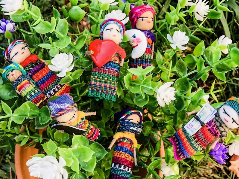 Puede incluir: Una colecci&oacute;n de mu&ntilde;ecas tejidas de colores con varios dise&ntilde;os y patrones. Las mu&ntilde;ecas est&aacute;n hechas de tela y tienen caras bordadas. Algunas de las mu&ntilde;ecas sostienen objetos, como un coraz&oacute;n, una luna y un trozo de papel.