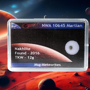 Può includere: Un campione di meteorite marziano in una teca trasparente. L'etichetta recita "NWA 10645 Martian, Nakhilite, Found - 2016, TKW - 12g". Lo sfondo presenta un pianeta rosso e altri corpi celesti.