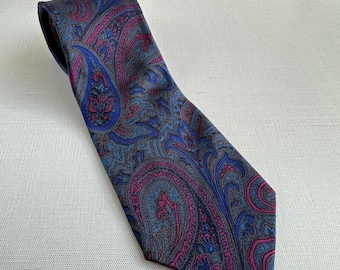 Könnte beinhalten: Eine gemusterte Krawatte mit einem Paisley-Design in Blau-, Rosa- und Grautönen. Die Krawatte ist aus einem glatten Stoff gefertigt und eignet sich für formelle oder geschäftliche Anlässe. Das komplizierte Muster verleiht Eleganz.