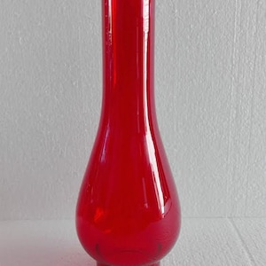 May include: A red glass lamp chimney with a rounded base and a tall, narrow neck.