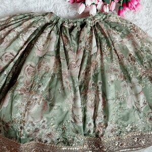 May include: A green skirt with a floral print and gold sequins around the hem.