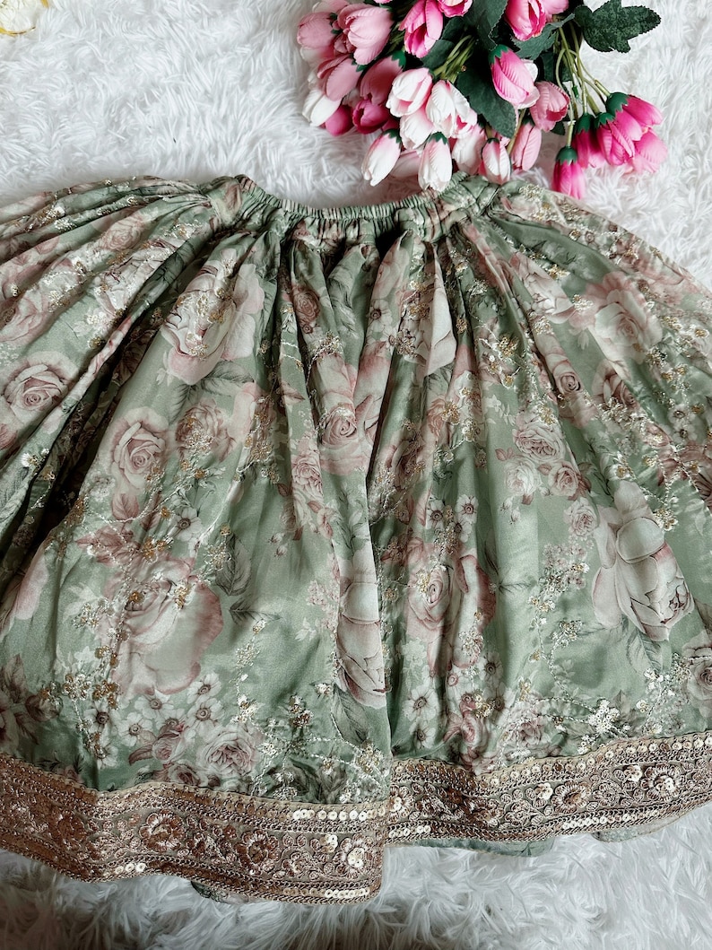 May include: A green skirt with a floral print and gold sequins around the hem.