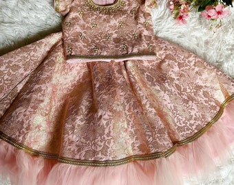Könnte beinhalten: Ein rosa und golden besticktes Kleid mit einem Tüllrock. Das Kleid hat einen runden Ausschnitt und kurze Ärmel. Der Rock hat einen goldenen Besatz und eine Schicht Tüll.