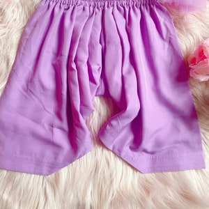 May include: A pair of lavender-coloured shorts with an elastic waistband. The shorts are made of a soft, lightweight fabric and have a relaxed fit.