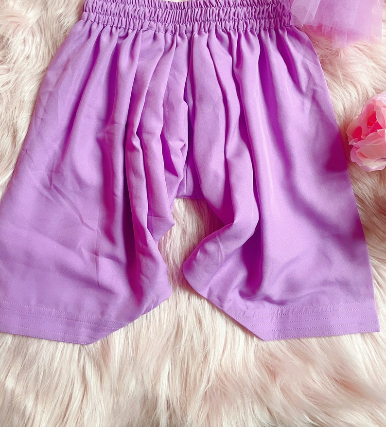 May include: A pair of lavender-coloured shorts with an elastic waistband. The shorts are made of a soft, lightweight fabric and have a relaxed fit.