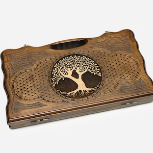 May include: A wooden game box with a carved tree of life design. The box is brown with a light wood inlay. The box has a hinged lid and a brass handle.