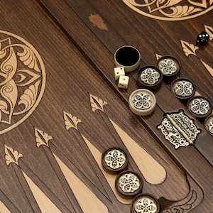 May include: A wooden backgammon set with intricate carvings and a traditional design. The set includes a wooden board, dice, and playing pieces.