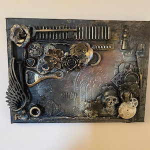 May include: A mixed media artwork with a dark background and gold accents. The piece features a skull, gears, a bottle opener, a key, and flowers. The text "Club Beer" is visible on the bottle opener.