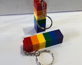 May include: Two rainbow-colored Lego brick keychain sets with silver key rings. Each set is made of six bricks, stacked vertically, with the colors red, orange, yellow, green, blue, and purple.