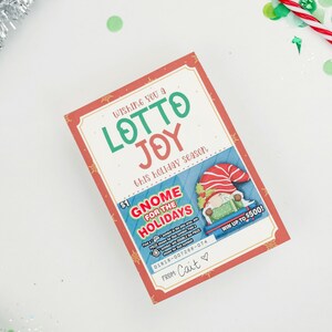 以下が含まれることがあります： ノームのイラストが描かれた、赤と白のクリスマスをテーマにしたスクラッチくじ。チケットには「Wishing you a Lotto Joy this holiday season.」と「Gnome for the Holidays.」と書かれている。また、「Win up to &yen;500!」と「From Cait.」という署名も書かれている。