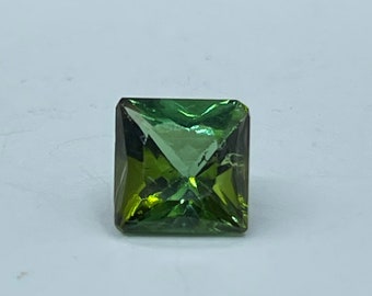 May include: A green gemstone with a square cut, set on a white background.