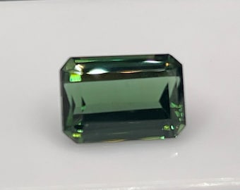 May include: A green gemstone with a rectangular emerald cut.