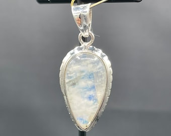 May include: A silver pendant with a teardrop-shaped moonstone. The stone has a white and blue iridescent sheen.