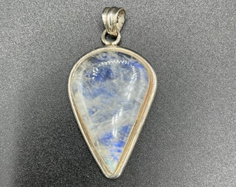 May include: A teardrop-shaped pendant with a silver setting and a clear moonstone with blue iridescent flashes.