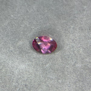 Puede incluir: Una piedra preciosa ovalada de color rosa con un ligero brillo.