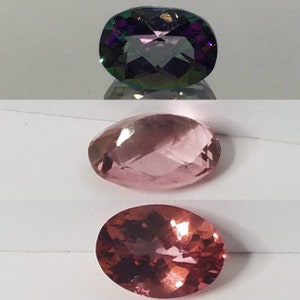 Puede incluir: Tres piedras preciosas de forma ovalada. La piedra superior es de color morado oscuro con matices iridiscentes verdes y azules. La piedra del medio es de color rosa claro con un ligero brillo. La piedra inferior es de color rosa oscuro con un ligero brillo.