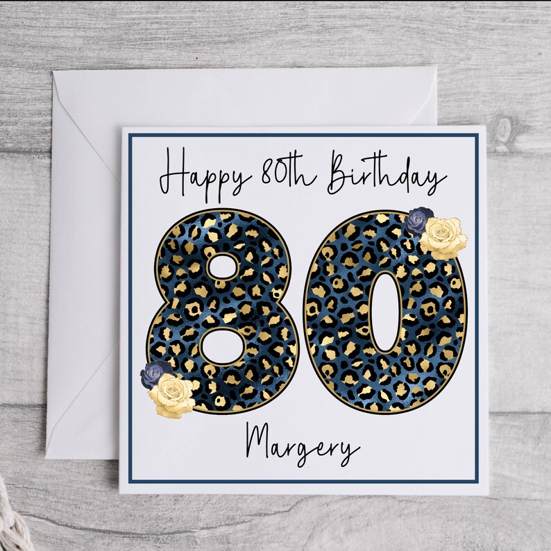 Puede incluir: Una tarjeta blanca con un dise&ntilde;o de estampado de leopardo azul y dorado. La tarjeta dice "Happy 80th Birthday" y "Margery".