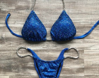 May include: A blue sparkly bikini with silver straps. The top is a triangle style and the bottom is a cheeky cut.