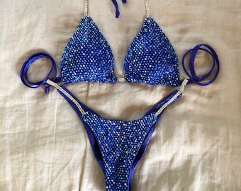 May include: A blue and silver sequined bikini with a halter top and a high-cut bottom.
