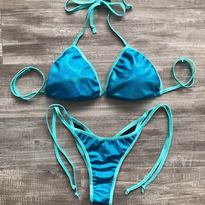 May include: A turquoise bikini with a triangle top and a high-cut bottom. The bikini has a shimmery finish and is made of a stretchy fabric.
